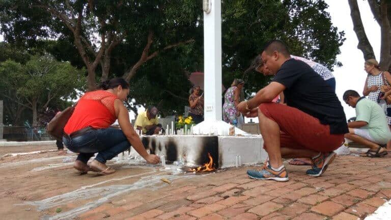 Pessoas orando e acendendo velas, e ambulantes vendendo: o ambiente no cemitério