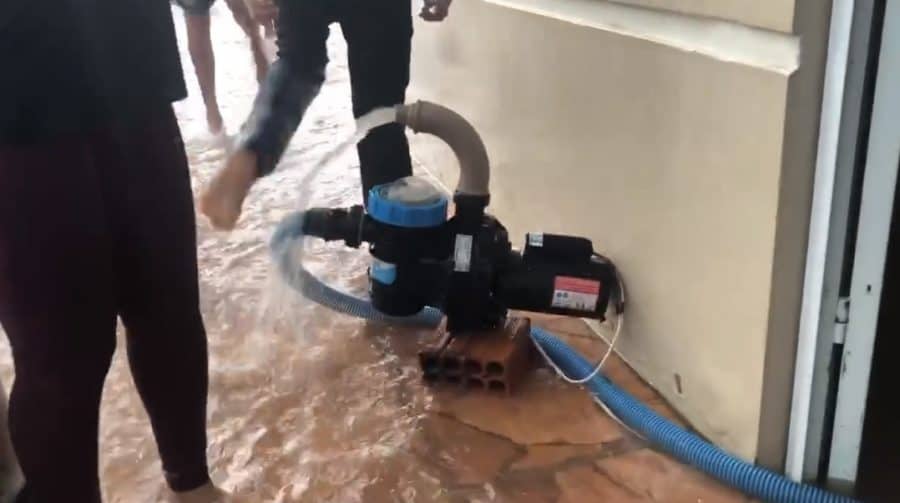 Moradora utiliza bomba para escoar água que invadiu sua casa