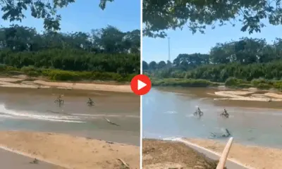 Adolescentes atravessam rio de bicicleta em meio à seca no Jordão