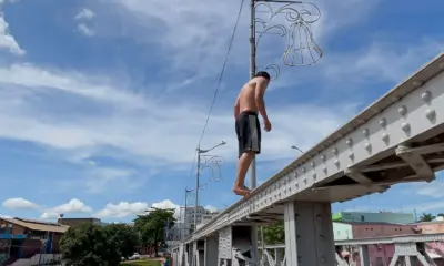 Adolescentes se arriscam pulando da ponte metálica durante cheia do Rio Acre